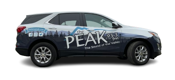 A dark-colored SUV with "Peak 93.3 FM" and mountain graphics on the side, promoting a radio station with the slogan "The Sound of the Valley.