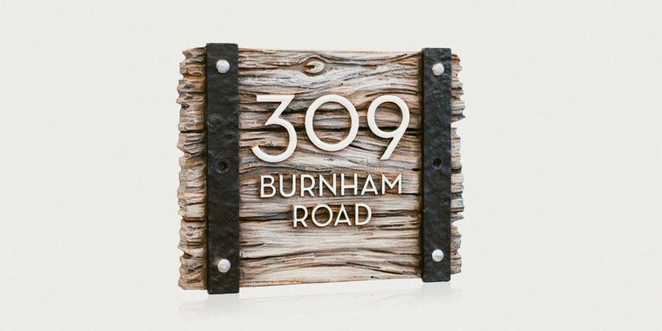 Wooden sign with black metal brackets displaying the address "309 Burnham Road" in white text.