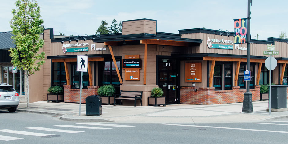 A street view of an insurance office building with signs reading "InsuranceCentres Vancouver Island" and "ICBC Autoplan." The building has large windows and a pedestrian crossing sign nearby.