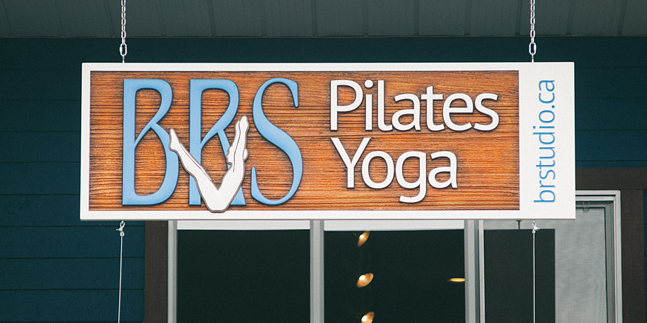 A sign for "BRS Pilates Yoga" hangs outside a building, featuring the website "brstudio.ca" on the right side.