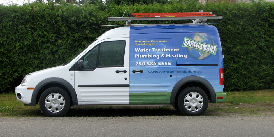 Side view of a white and green Earth Smart van with a ladder on top, advertising water treatment, plumbing, and heating services, along with a contact phone number and website.