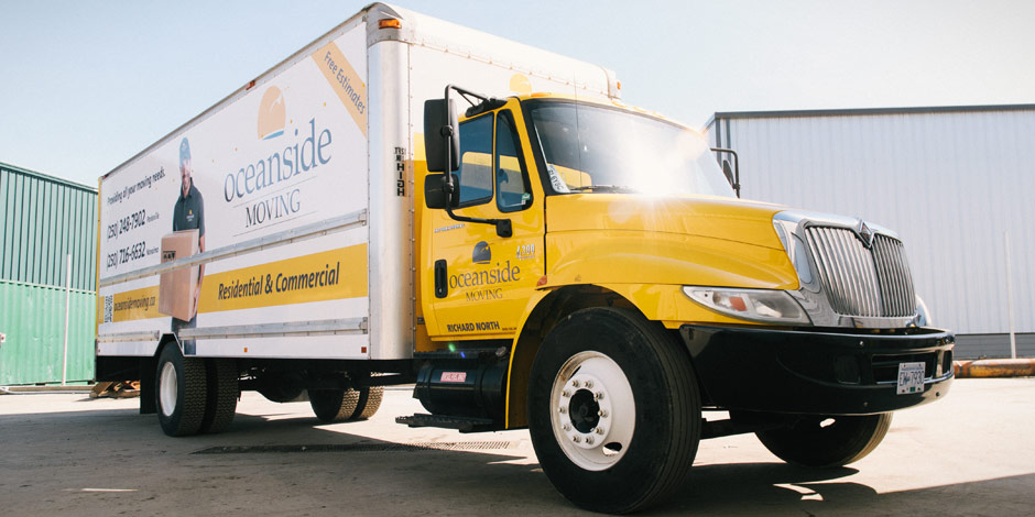 A yellow moving truck with "Oceanside Moving" branding is parked outside a building. The truck offers residential and commercial moving services and displays contact information and a logo.