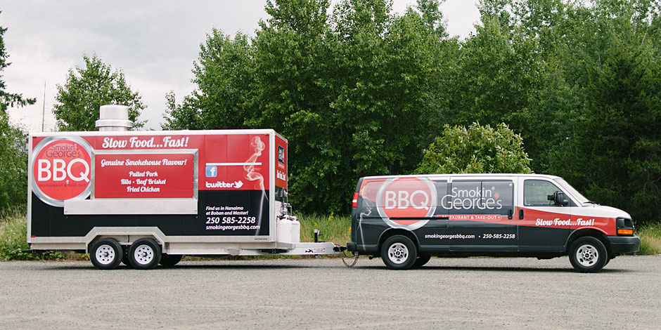 A white van with "Smokin' George's BBQ" branding is hitched to a food trailer in a parking lot. The trailer advertises pork, ribs, and fried chicken. Trees are visible in the background.