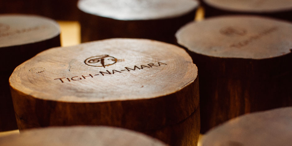 Close-up of several wooden discs, each engraved with the text "Tigh-Na-Mara" and a stylized logo.