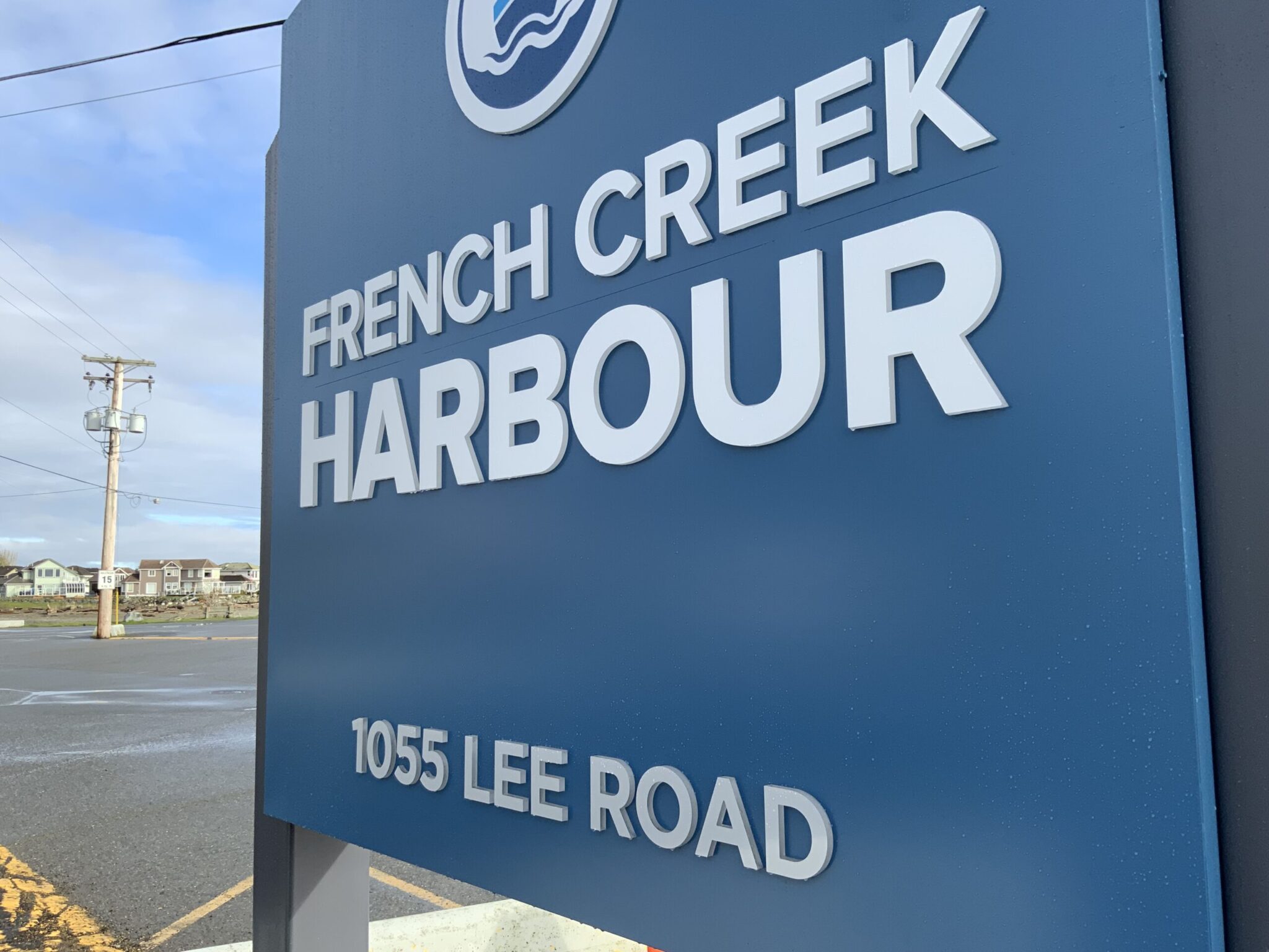 Sign for French Creek Harbour located at 1055 Lee Road, with overcast sky and surrounding buildings in the background.